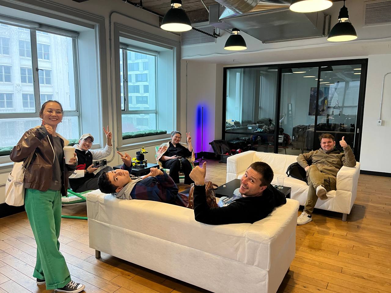 Friends hanging out on couches in the lounge giving thumbs up